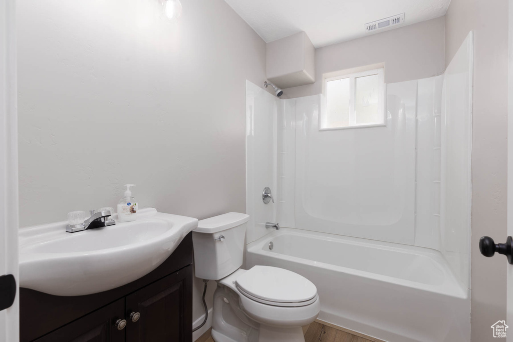 Bathroom featuring toilet, shower / bath combination, vanity, and wood finished floors