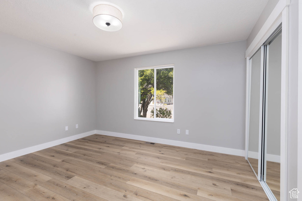 Unfurnished bedroom featuring a closet, baseboards, and light wood-style flooring