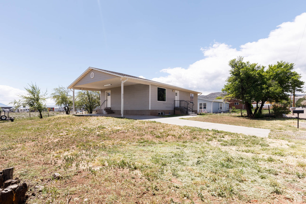 View of front facade featuring a front yard and a carport