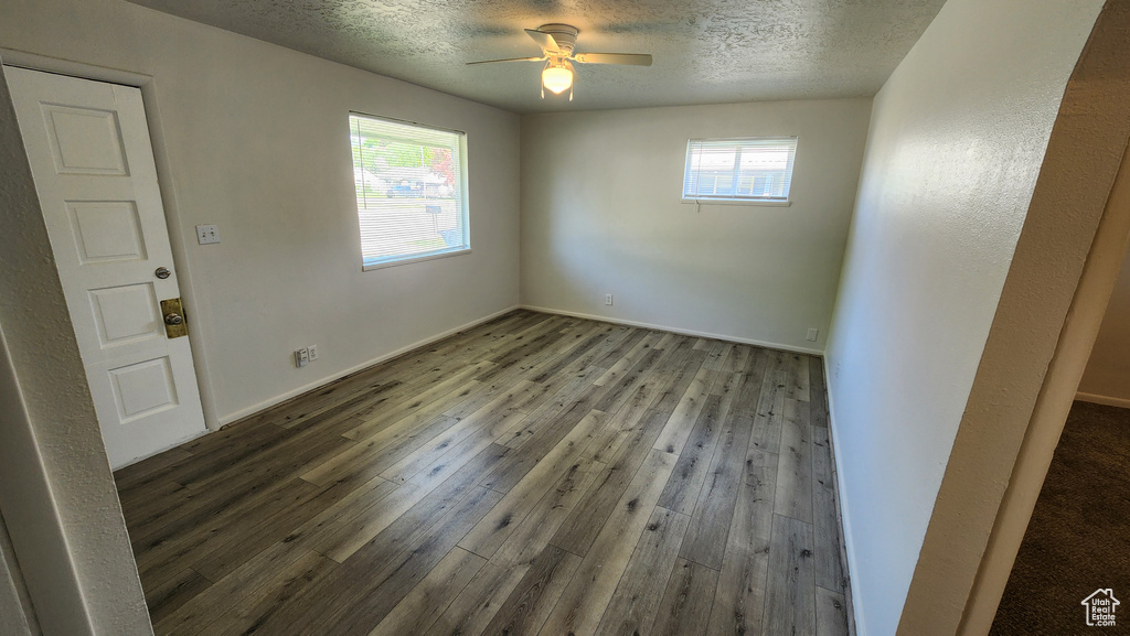 Spare room featuring hardwood / wood-style floors, plenty of natural light, a textured ceiling, ceiling fan, and baseboards