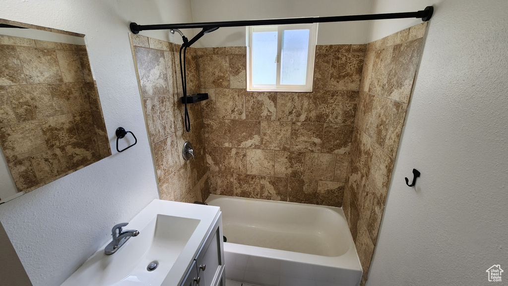 Bathroom with shower / bathtub combination, vanity, and a textured wall