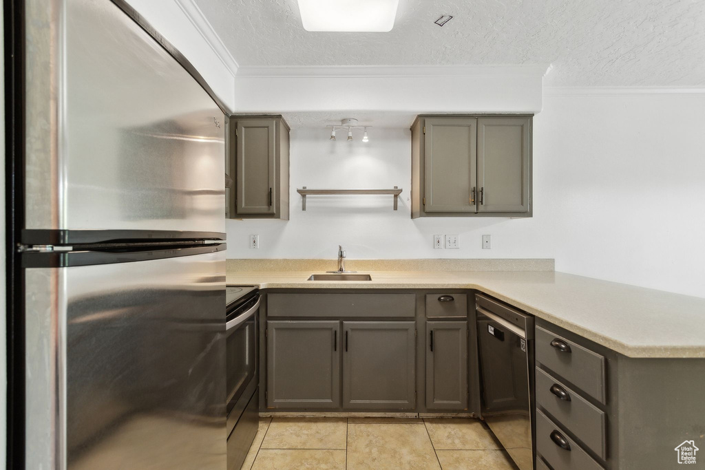 Kitchen with stainless steel appliances, a sink, a textured ceiling, ornamental molding, and light countertops