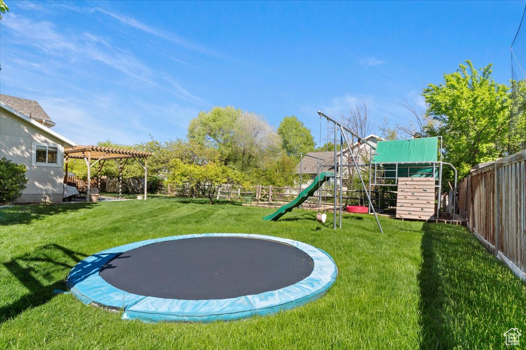 View of yard with a trampoline, a playground, and a pergola