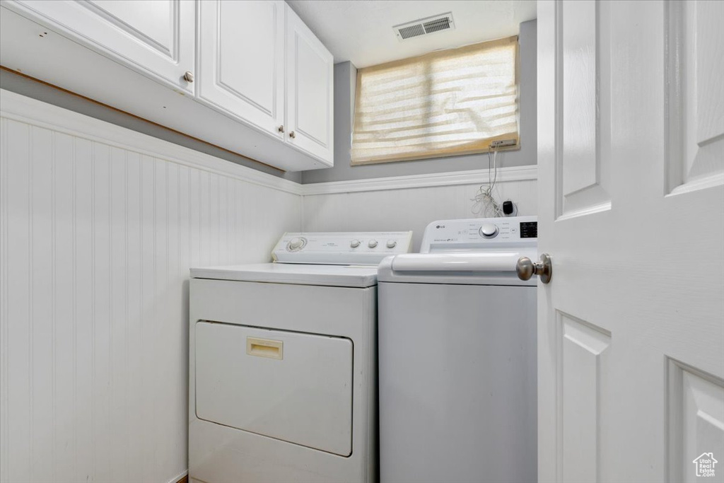 Washroom featuring cabinet space and independent washer and dryer