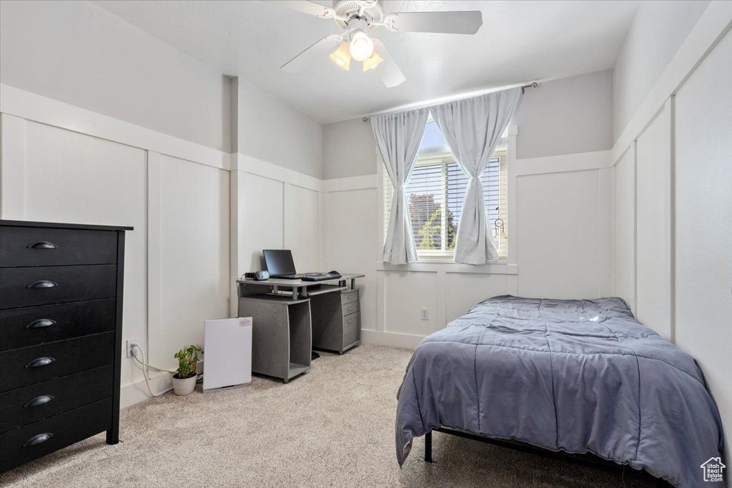 Bedroom featuring carpet floors, a decorative wall, multiple closets, a wainscoted wall, and a ceiling fan