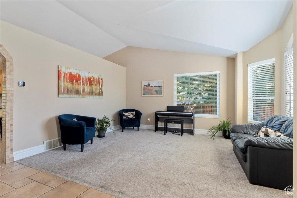 Living area featuring arched walkways, baseboards, vaulted ceiling, and carpet