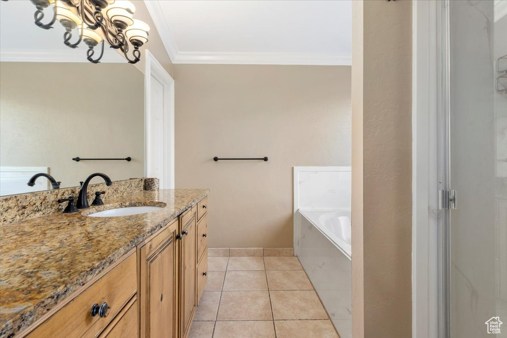 Full bathroom with vanity, ornamental molding, tile patterned floors, a garden tub, and a chandelier