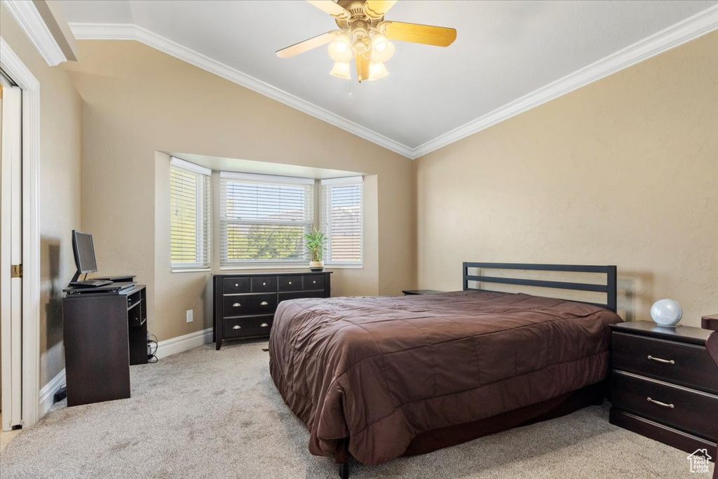 Carpeted bedroom with lofted ceiling, ornamental molding, baseboards, and ceiling fan