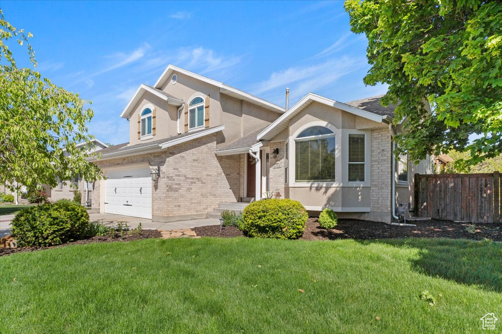 View of front of house featuring brick siding, stucco siding, and a garage