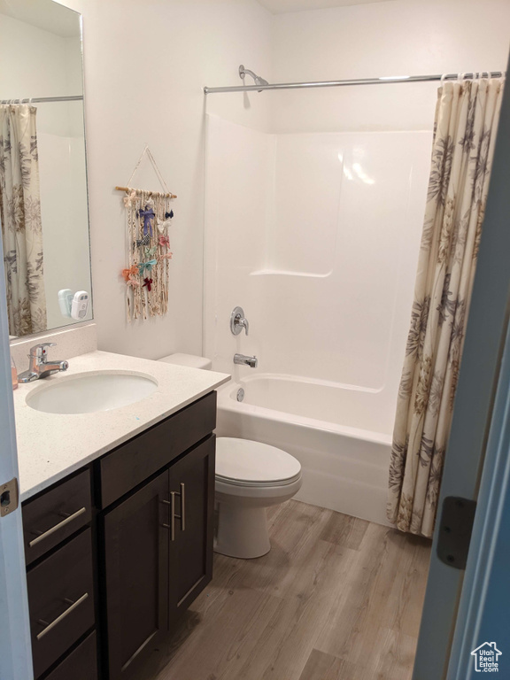 Bathroom with toilet, wood finished floors, shower / bath combo, and vanity