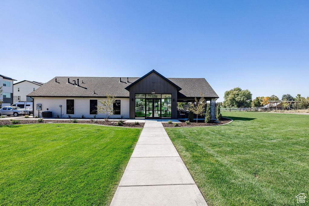 View of front of house featuring a front lawn, roof with shingles, board and batten siding, and cooling unit