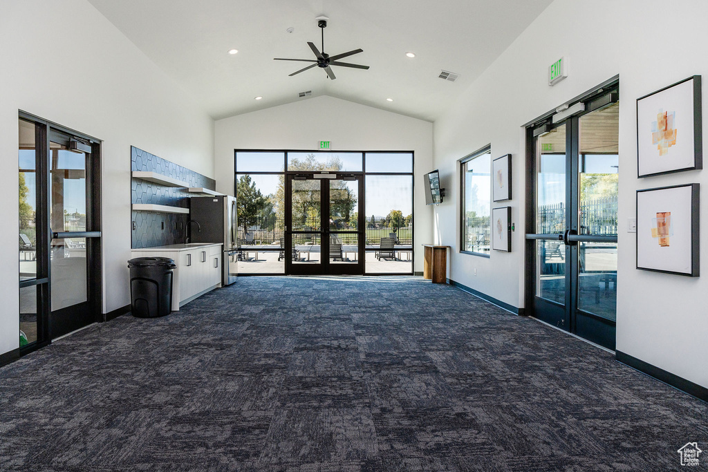 Unfurnished living room with french doors, dark carpet, high vaulted ceiling, a ceiling fan, and baseboards