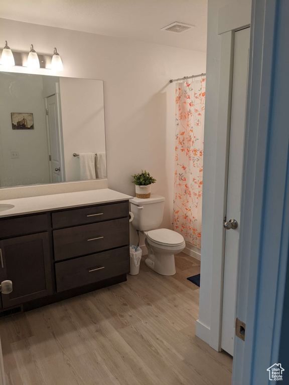 Full bathroom with visible vents, wood finished floors, vanity, toilet, and a shower with shower curtain