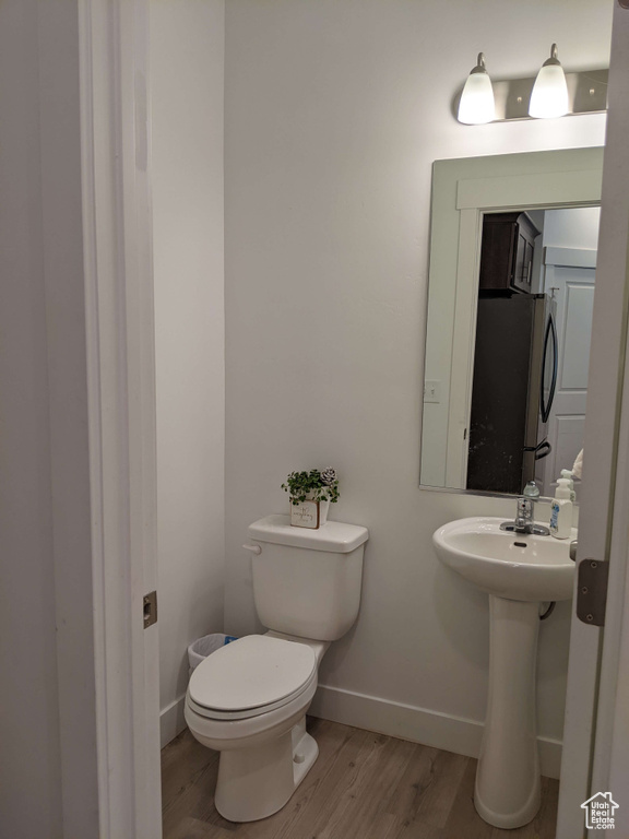 Bathroom featuring baseboards, a sink, wood finished floors, and toilet
