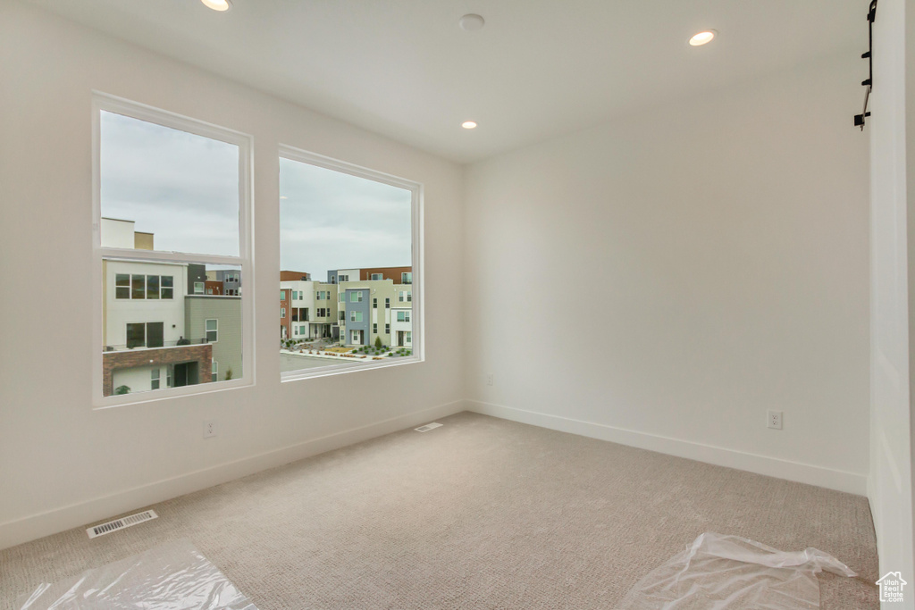 Carpeted spare room with baseboards and recessed lighting