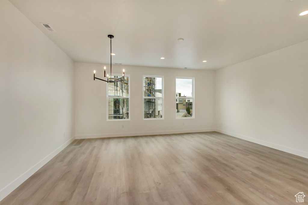 Spare room featuring a chandelier, light wood finished floors, baseboards, and recessed lighting