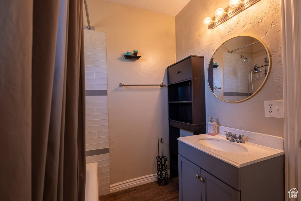 Bathroom with vanity, a shower with shower curtain, and wood finished floors