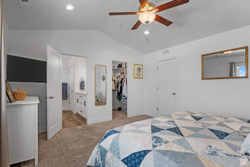 Bedroom with light carpet, vaulted ceiling, a spacious closet, ceiling fan, and a closet