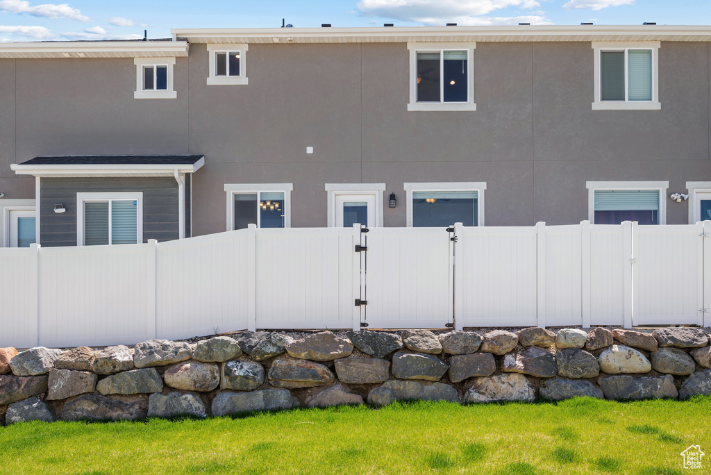 Back of house with fence, stucco siding, and a gate