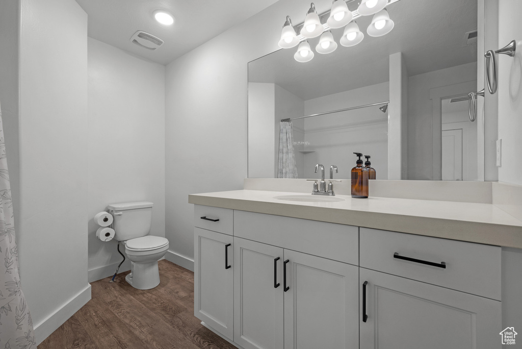 Bathroom featuring toilet, wood finished floors, baseboards, vanity, and a shower with shower curtain