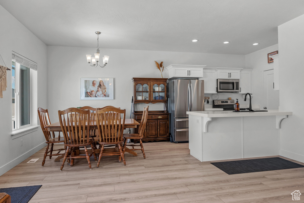 Dining space with a chandelier, recessed lighting, light wood-style floors, and baseboards