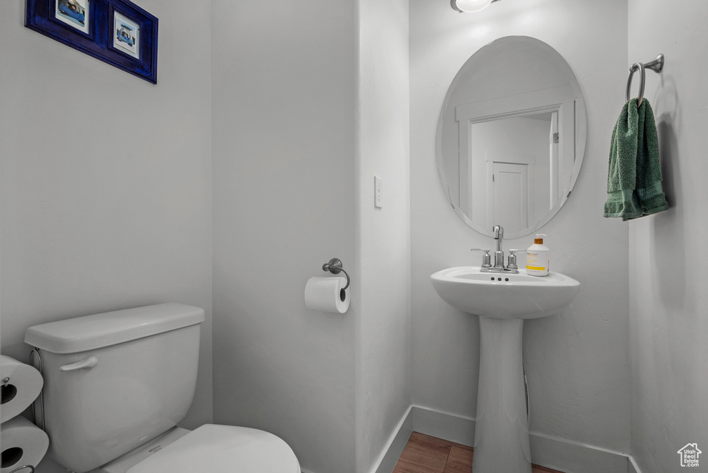 Half bath with toilet, wood finished floors, and baseboards