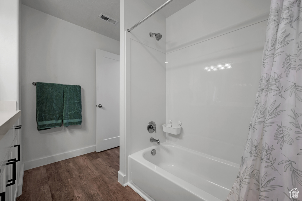 Bathroom featuring wood finished floors, shower / tub combo with curtain, baseboards, and vanity