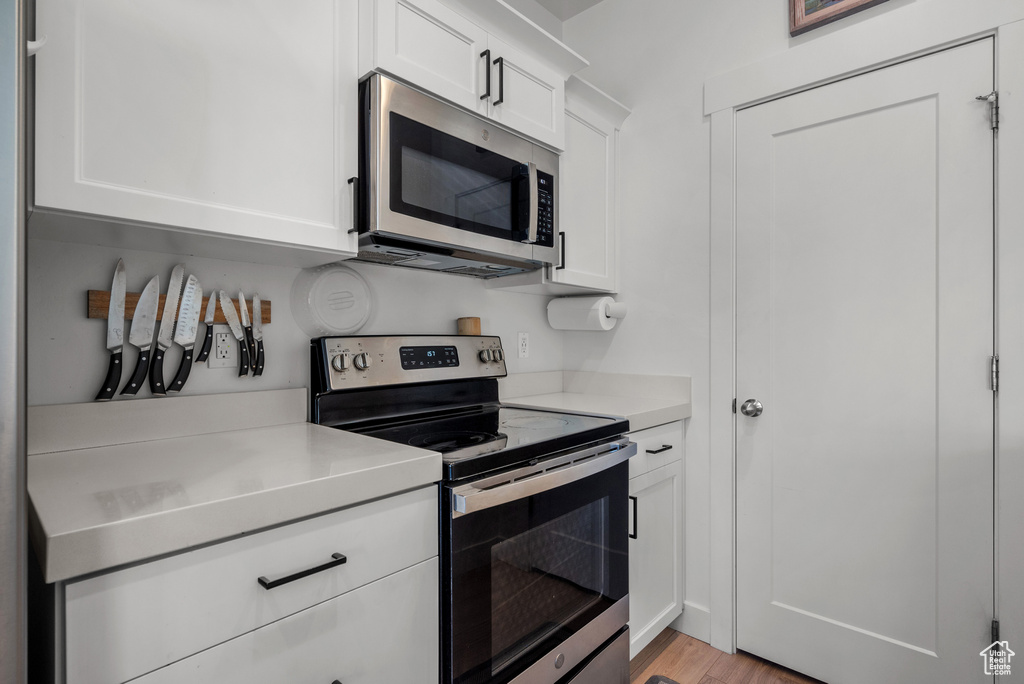 Kitchen with appliances with stainless steel finishes, light countertops, white cabinetry, and light wood-style flooring