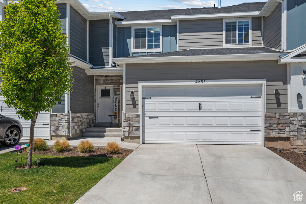 View of front of home with stone siding, an attached garage, and concrete driveway