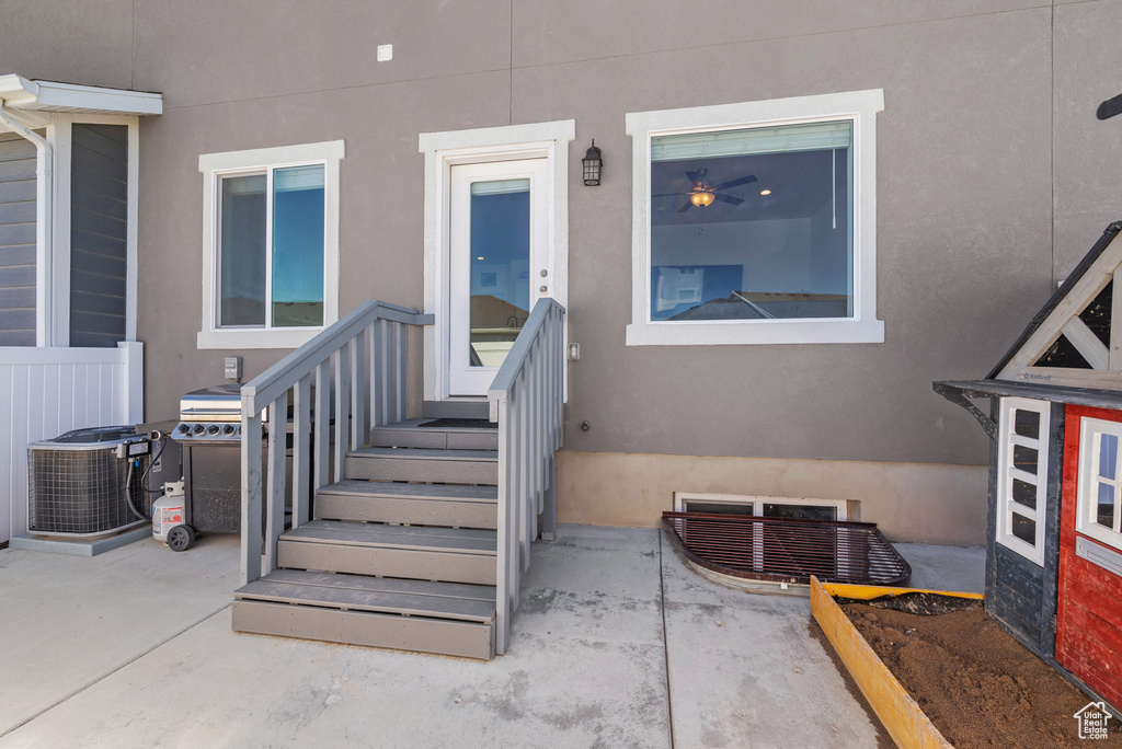 View of exterior entry with stucco siding and central AC unit