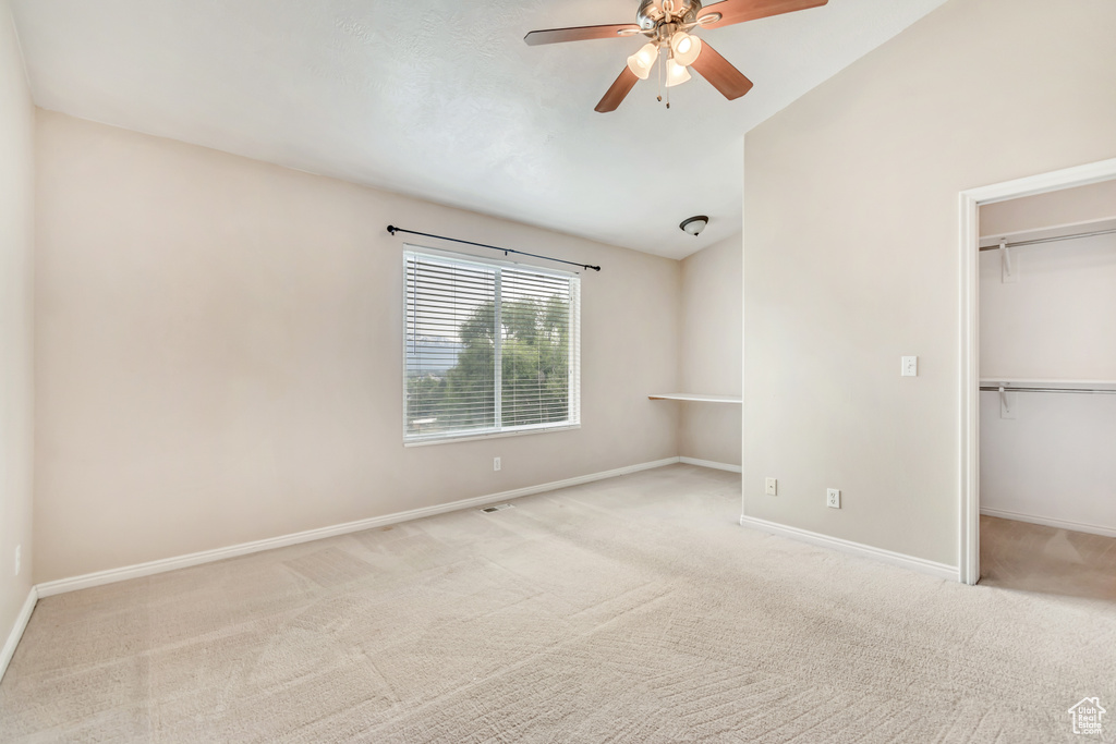 Unfurnished bedroom featuring carpet floors, baseboards, a closet, a spacious closet, and lofted ceiling