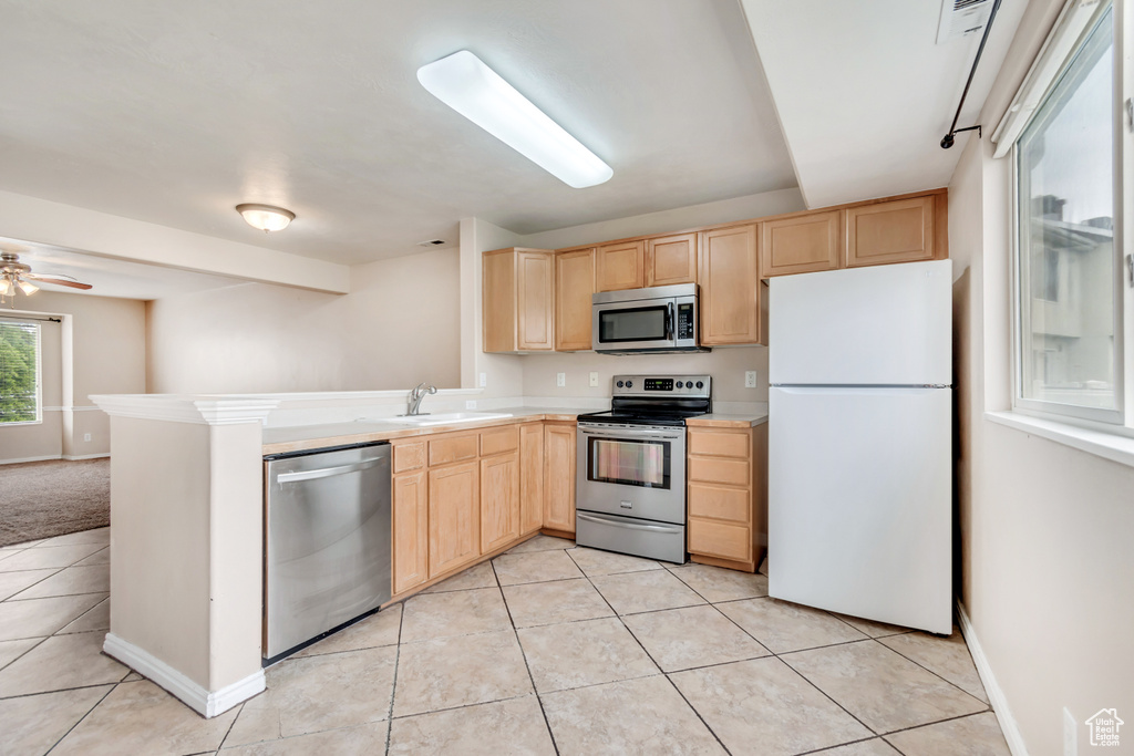 Kitchen featuring stainless steel appliances, light brown cabinetry, a sink, and light tile patterned flooring
