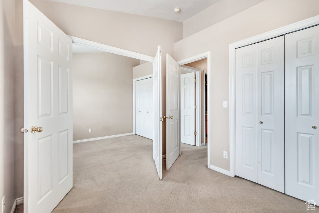 Unfurnished bedroom with light carpet and baseboards