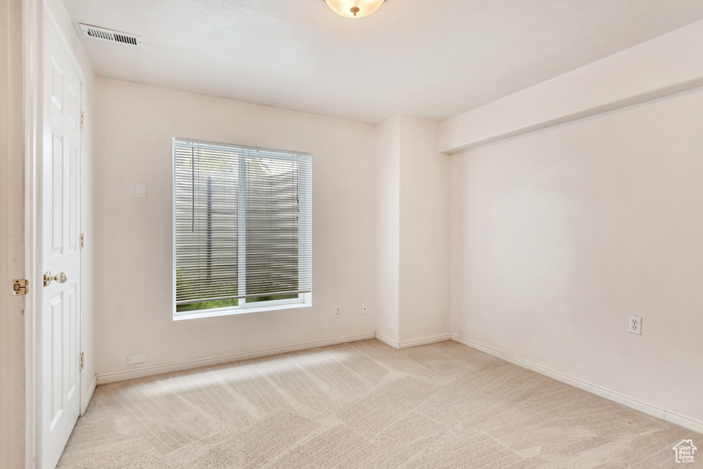 Spare room featuring light colored carpet and baseboards