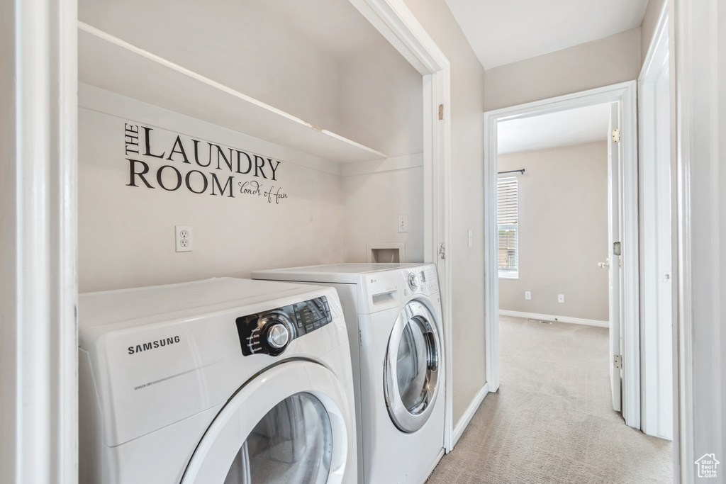 Laundry room featuring washing machine and dryer, light carpet, and baseboards