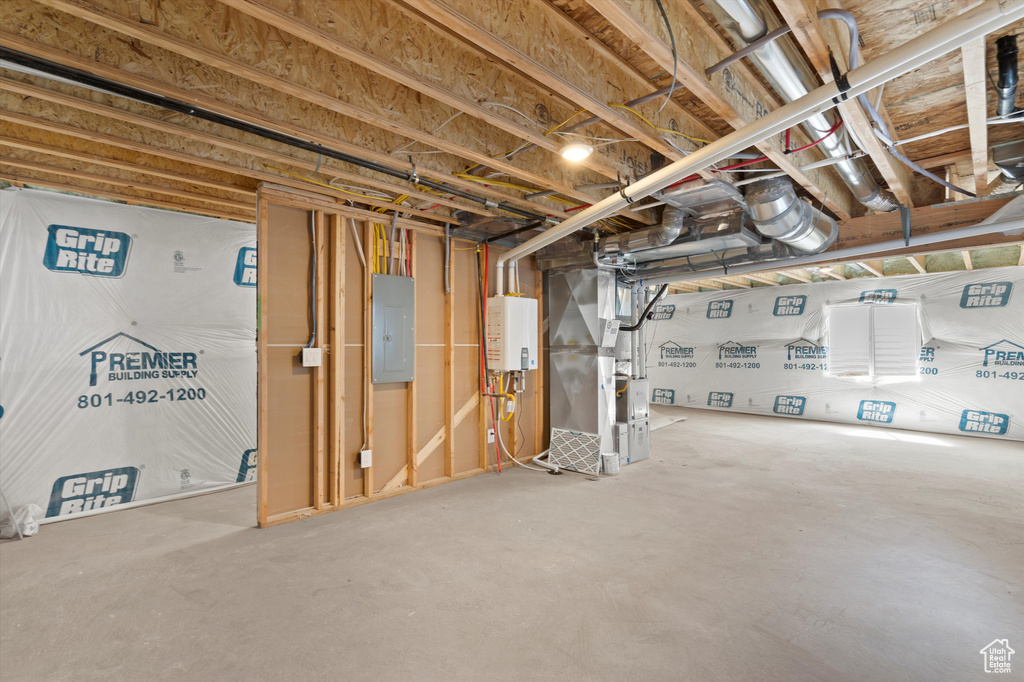 Unfinished below grade area featuring heating unit, tankless water heater, and electric panel