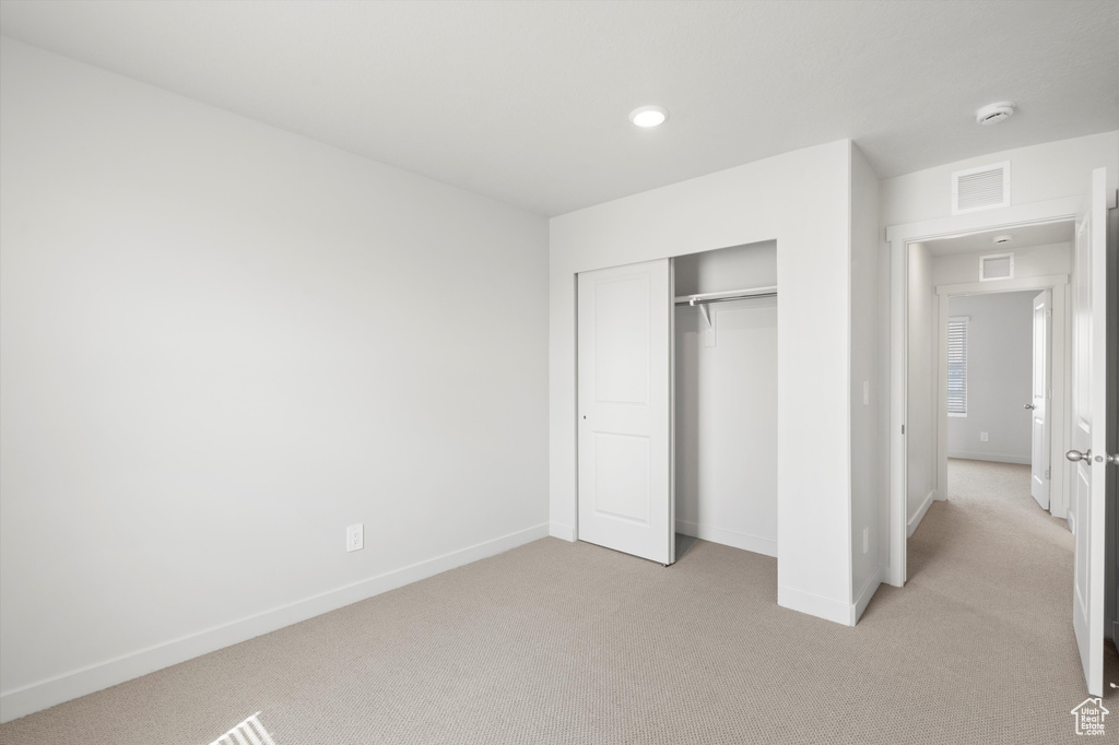 Unfurnished bedroom featuring light carpet, a closet, and recessed lighting