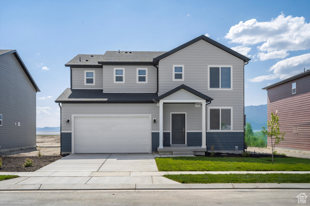 View of front facade featuring an attached garage, concrete driveway, a front lawn, and a shingled roof
