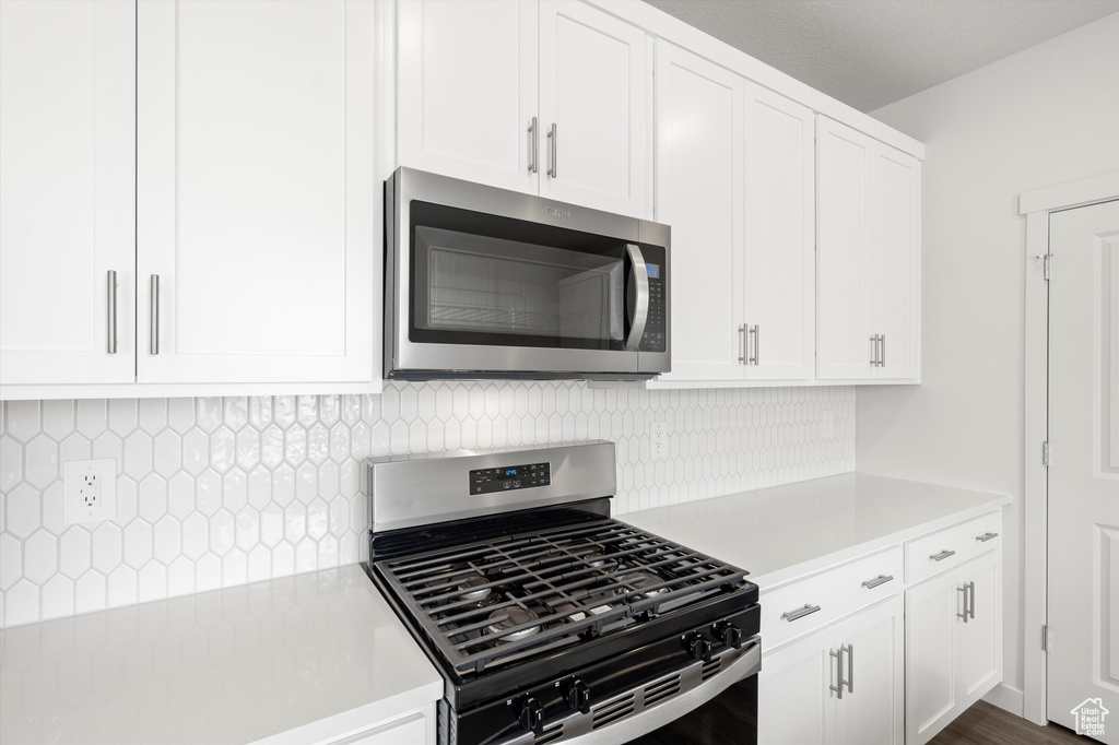 Kitchen with stainless steel appliances, light countertops, tasteful backsplash, and white cabinets