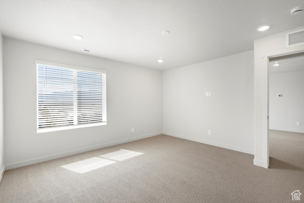 Empty room with light carpet and recessed lighting