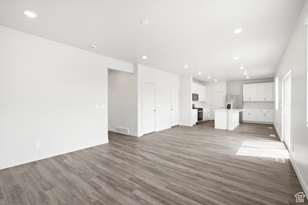 Unfurnished living room with wood finished floors and recessed lighting