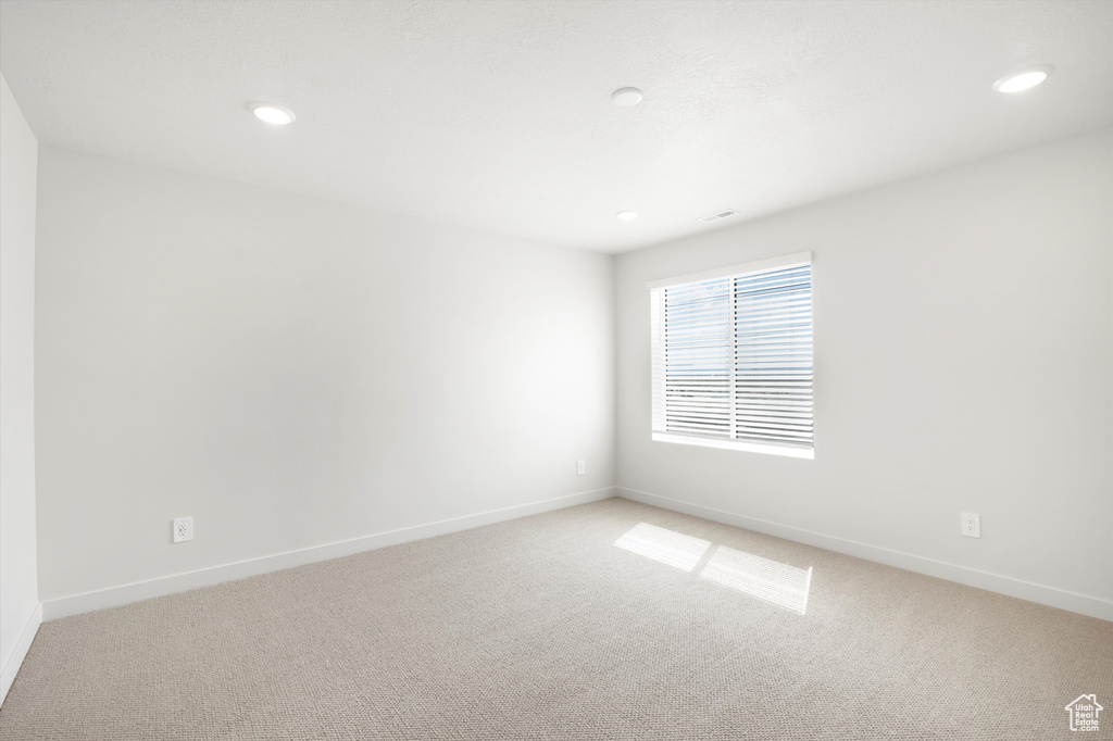 Spare room featuring light colored carpet and recessed lighting
