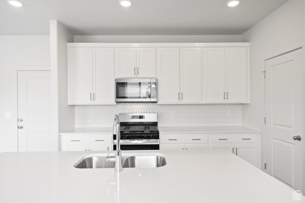 Kitchen featuring stainless steel appliances, white cabinetry, light countertops, and recessed lighting