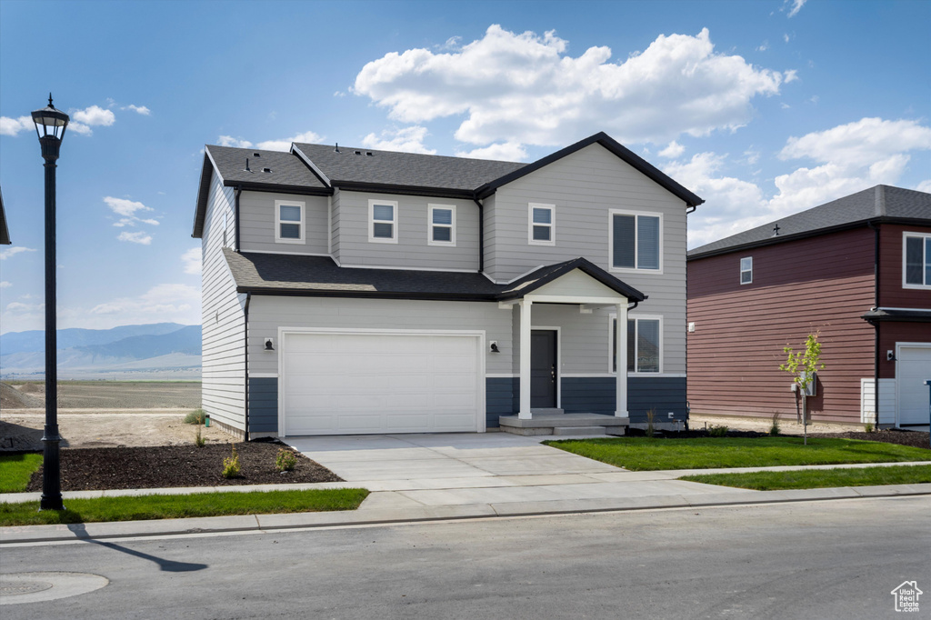 Traditional-style home featuring a garage, concrete driveway, a mountain view, and roof with shingles