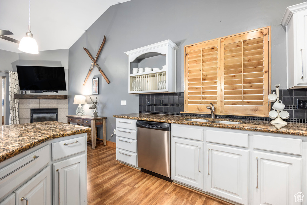 Kitchen with stainless steel dishwasher, light wood-style floors, a sink, and tasteful backsplash