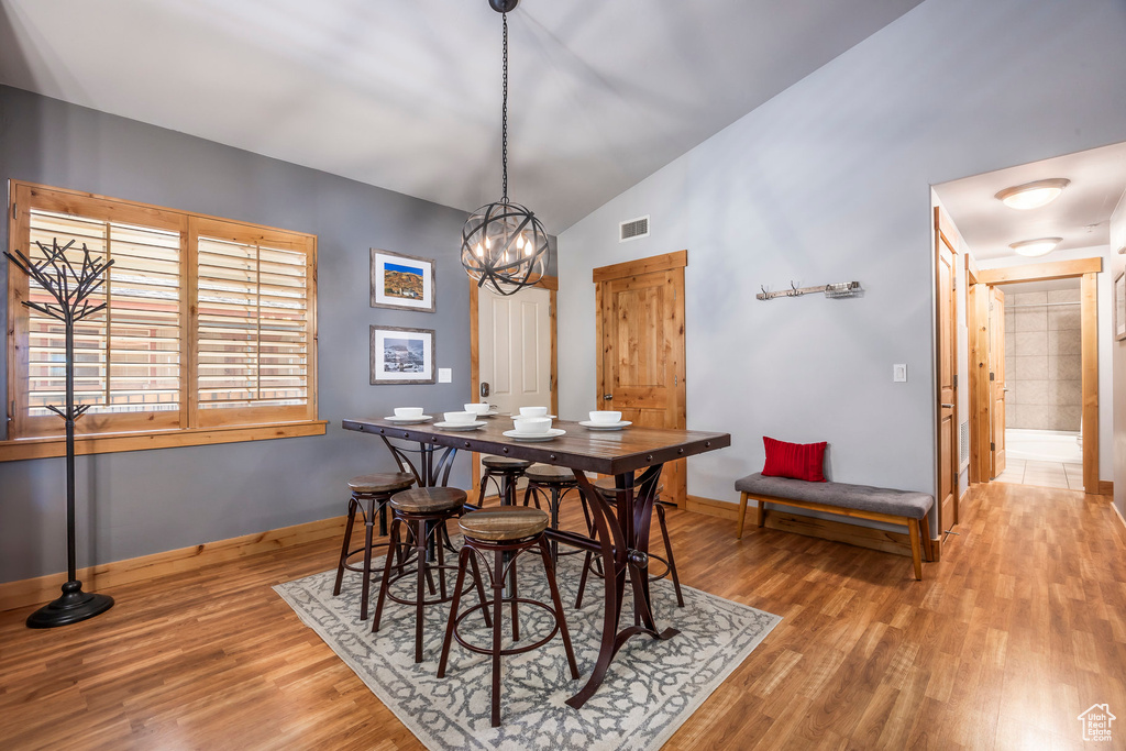 Dining room featuring visible vents, an inviting chandelier, wood finished floors, baseboards, and vaulted ceiling