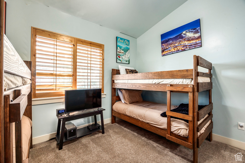 Bedroom featuring carpet flooring, baseboards, and lofted ceiling