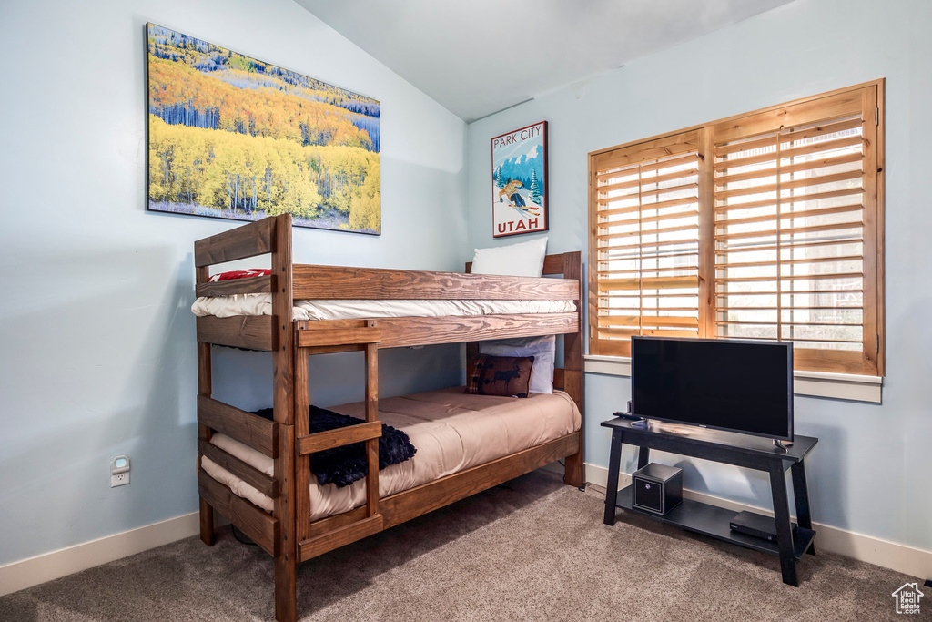 Carpeted bedroom featuring baseboards and vaulted ceiling
