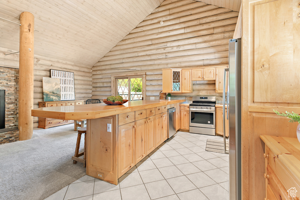 Kitchen featuring light brown cabinetry, wooden ceiling, rustic walls, a peninsula, and stainless steel appliances