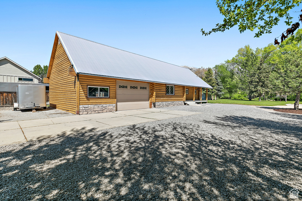 Exterior space featuring stone siding, concrete driveway, a garage, and metal roof